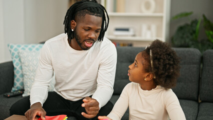 African american father and daughter sitting on sofa speaking at home