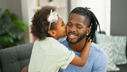 African american father and daughter smiling confident hugging each other sitting on sofa kissing at home