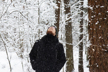 A bearded red-haired guy looks at the sky in a winter forest. The guy is looking at the top.