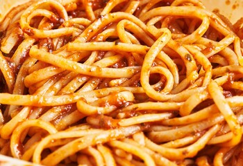 Close-up of spaghetti pasta coated in marinara sauce, evoking an italian culinary experience.