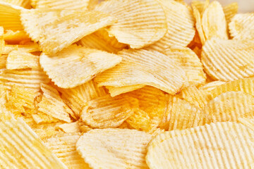 Close-up view of crispy, golden potato chips filling the frame, evoking a sense of snacking and indulgence.