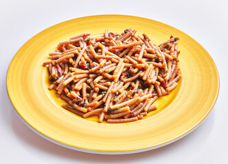 Close-up of a healthy wholegrain pasta dish served on a bright yellow plate against a white background.