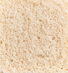 Close-up texture of a slice of white bread, showcasing its porous surface and soft appearance.