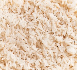 A close-up view of white cooked rice, showcasing its texture and individual grains, symbolizing...