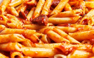 Close-up of penne pasta in tomato sauce with herbs, perfect for italian cuisine culinary concepts.