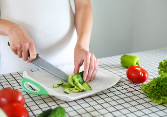 Young pregnant woman cooking vegetable salad at kitchen