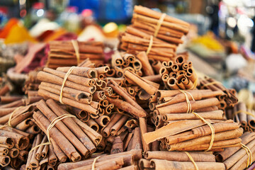 Piles of aromatic cinnamon sticks tied together, showcasing spices at an outdoor market.