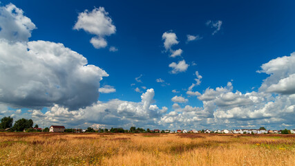 Obraz premium Summer village landscape with beautiful clouds.