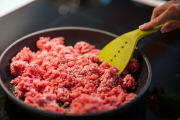 stirring mince meat in frying pan.