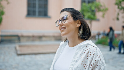 Beautiful young hispanic woman smiling confident looking to the side in the streets of Stockholm