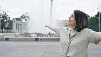 Young beautiful hispanic woman with open arms at Vienna fountain