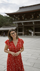 Cheerful beautiful hispanic woman with glasses posing confidently at traditional meiji temple, exuding success and joy in tokyo, japan