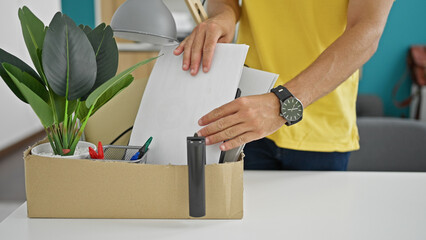 Young hispanic man being fired putting documents on document belongings package at the office