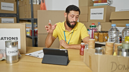 Young hispanic man volunteer having video call at charity center