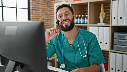 Young hispanic man doctor doing video call with computer smiling at the clinic