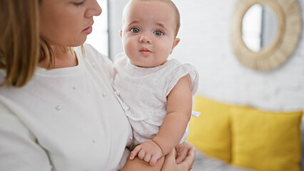 Mother standing in bedroom, arms lovingly hugging her daughter; a picture of relaxed family love
