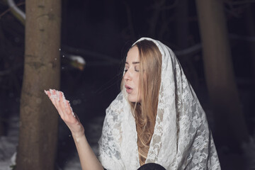 young blond woman with blue eyes dancing in the dark night of an very cold snow winter