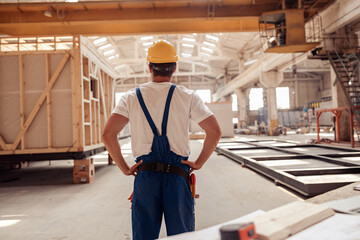 Male builder in safety helmet observing building under construction