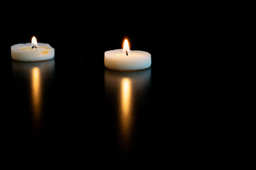 deux petites bougies blanches chauffe plat et leur reflet sur une table noire avec de l'espace vide