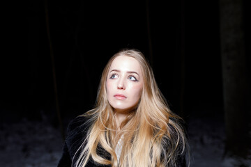 young blond woman with blue eyes dancing in the dark night of an very cold snow winter