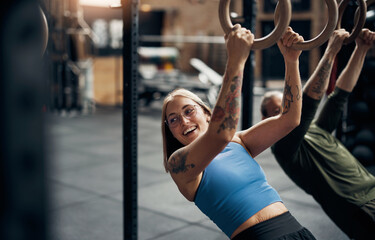 Smiling woman working out on rings during a gym exercise class
