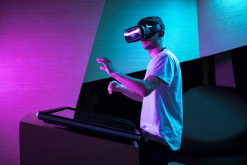 Young man interacting in a digital world, using virtual reality headset with motion tracking tech,...