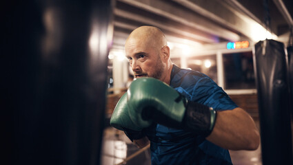 Mature man exercising with a punching bag in a boxing gym