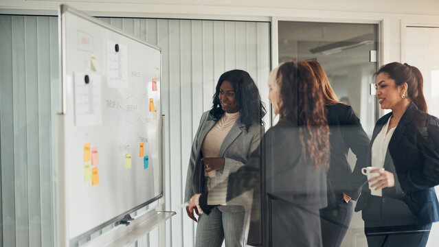 Smiling businesswomen brainstorming together on a whiteboard in an office
