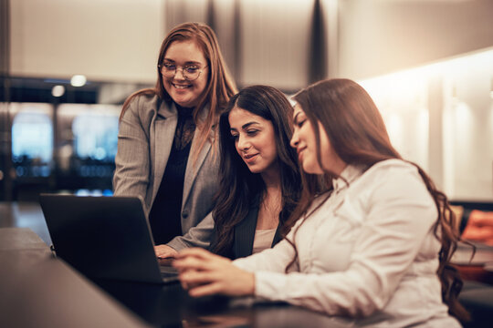 Smiling businesswomen working on a laptop in a hotel lobby during a trip