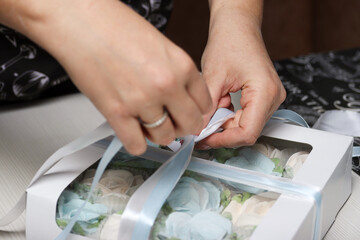 A woman is packing a gift. Zephyr in closed gift boxes.  Spruce cones from zephyr and Flowers from...