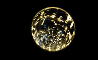 vase transparent avec une guirlande lumineuse à l'intérieur devant un fond noir vu d'en haut - texture abstraite