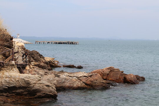 Seaside Serenity: A breathtaking view of the rocky Mediterranean coast, where waves gently caress the shore under the blue sky, creating a serene summer landscape