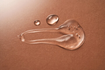 Fototapeta na wymiar A drop of transparent cosmetic gel on a beige background.