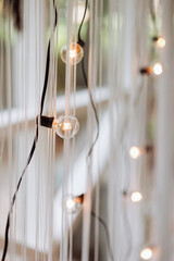 Hanging bulbs illuminate a serene space, casting a warm glow. The black wires create a vertical pattern. Concept: Interior design, lighting ideas, cozy atmosphere.