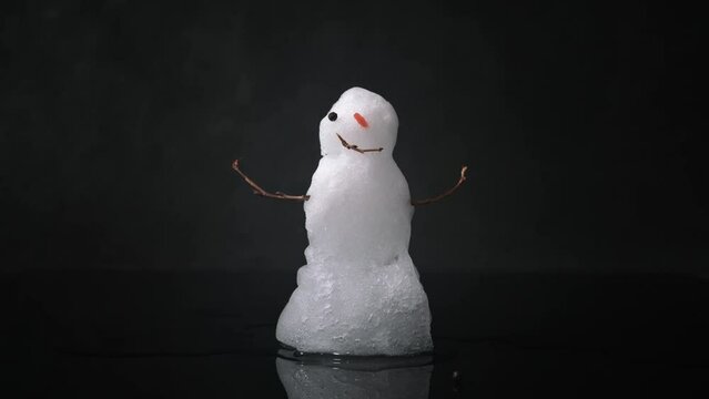 Snowman melting on black background. Real snowman melts quickly. Timelapse 4k video.