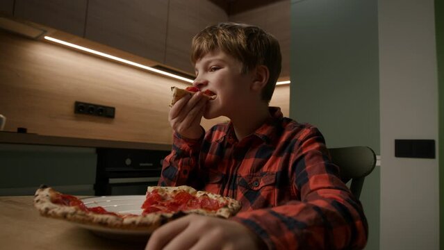 kid relishes a tasty pizza slice while engrossed in a tablet computer. Perfect for portraying the modern blend of tech and mealtime enjoyment