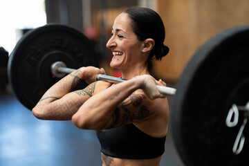 Smiling woman lifting weights in a cross training gym