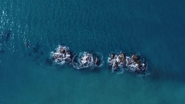 Onde del mare che si infrangono sugli scogli in mezzo al mare. Vista aerea dall'alto verso il basso dell'oceano - Panorama Azmut - Video 4k