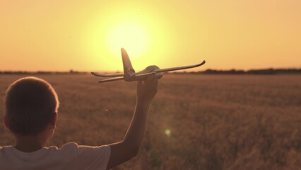 Boy plays with toy airplane, flying over field. Child dream, flight to future. Boy wants to become...