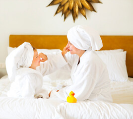 Happy mother and daughter in bathrobes with cream mask