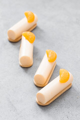 Tangerine cream cakes of cylindrical shape, dessert bars. On cookies. Decorated with a slice of tangerine. 