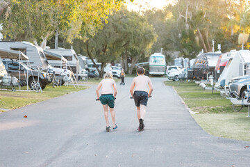 Kids riding scooters through caravan park on tropical holiday