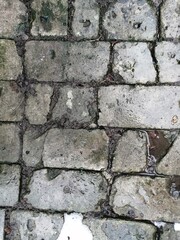 Obraz premium Paving a courtyard or path made of old split and cracked light bricks or concrete blocks.