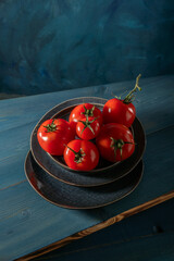 Tomatoes on a plate on a blue wooden table.