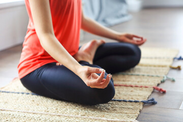 Attractive young woman exercising and sitting in yoga lotus position while resting at home