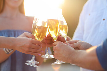 Happy friends with champagne sparkling wine in glasses outdoors at a beach