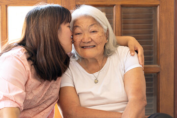 Affectionate Asian daughter kissing her mother at home. Mother's Day.