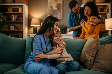 Loving parents look on with smiles as a home nurse shares a tender hug with their kid