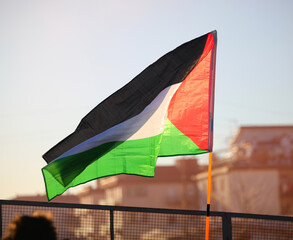 Palestinian flag flying in the suburban suburbs backlit at sunset