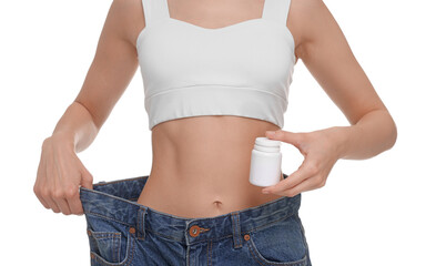 Slim woman in big jeans with bottle of pills on white background, closeup. Weight loss